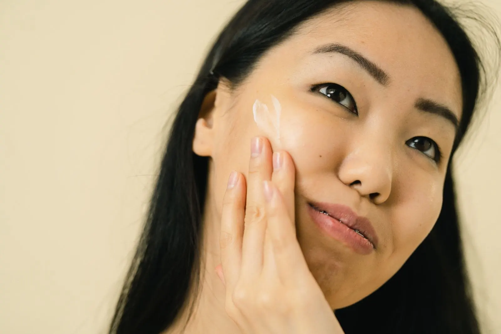 Cô gái chạm nhẹ lên má trên nền be