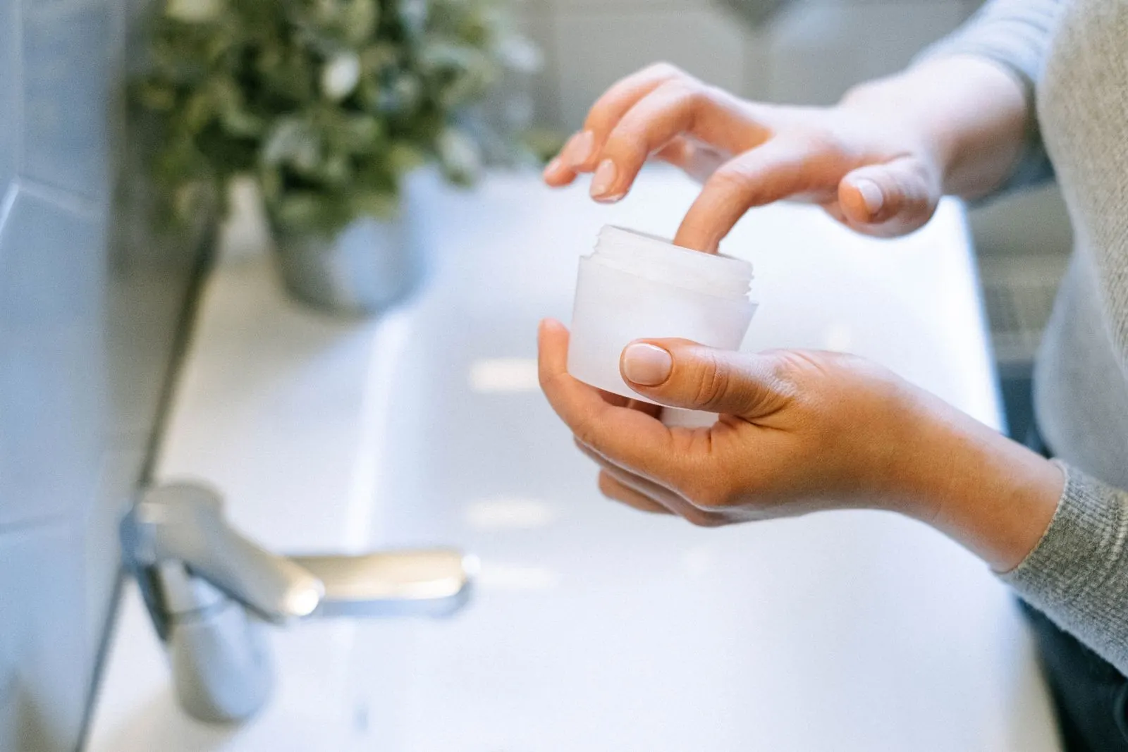 Lấy một chút kem từ hũ trên bồn rửa